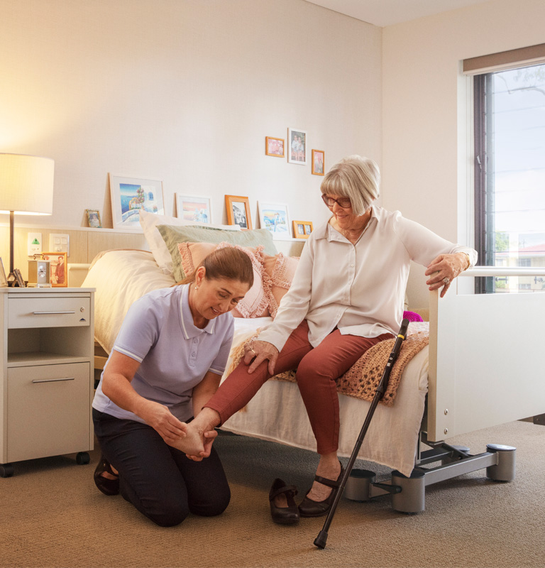 Healthcare worker helping lady put her shoes on