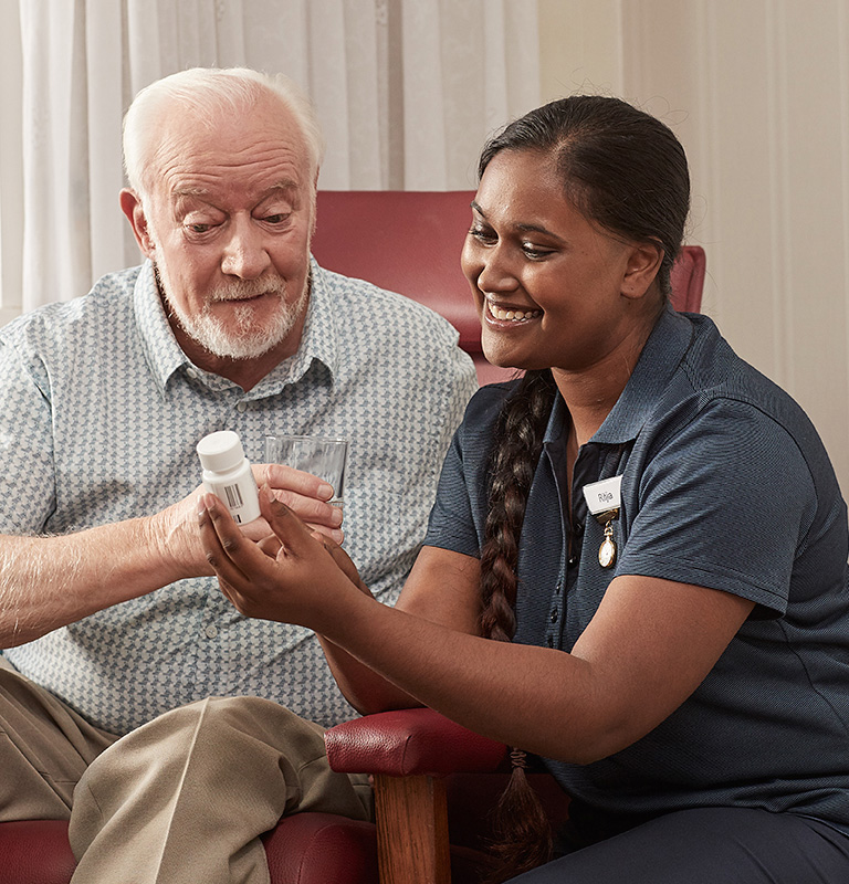 Elderly man and a carer looking at his medication