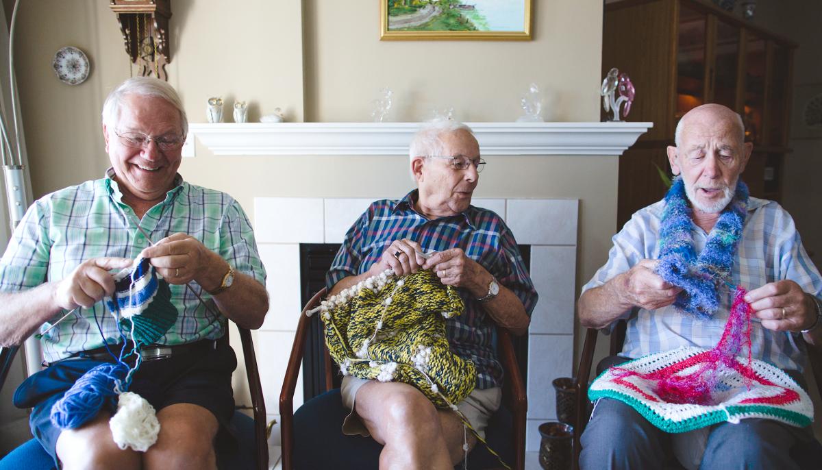 Three older men knitting