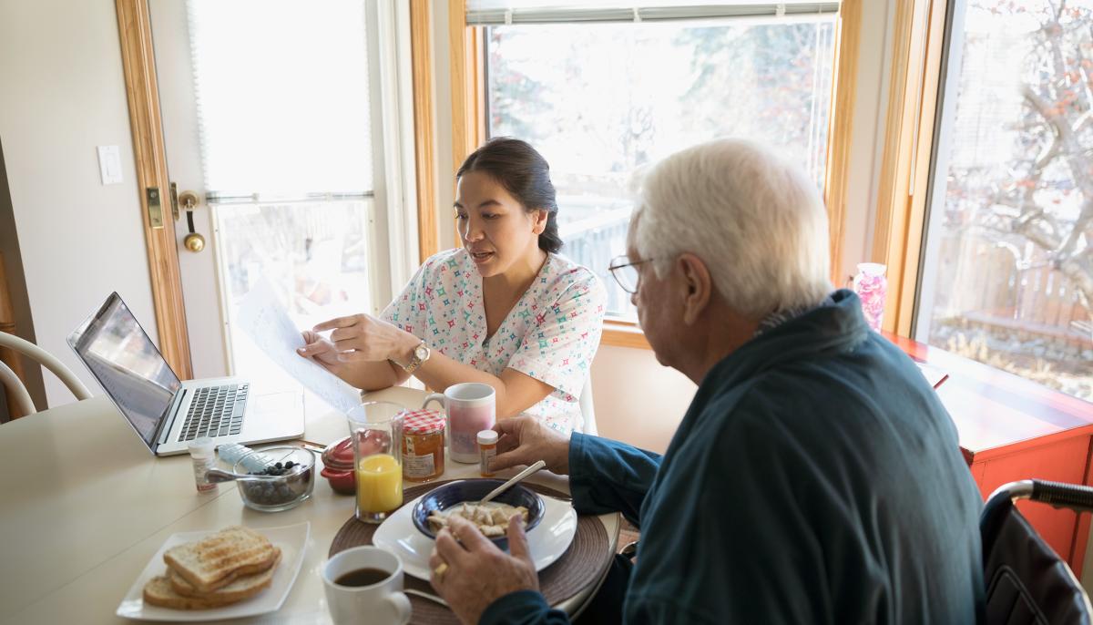 Aged care worker helping older man with paperwork