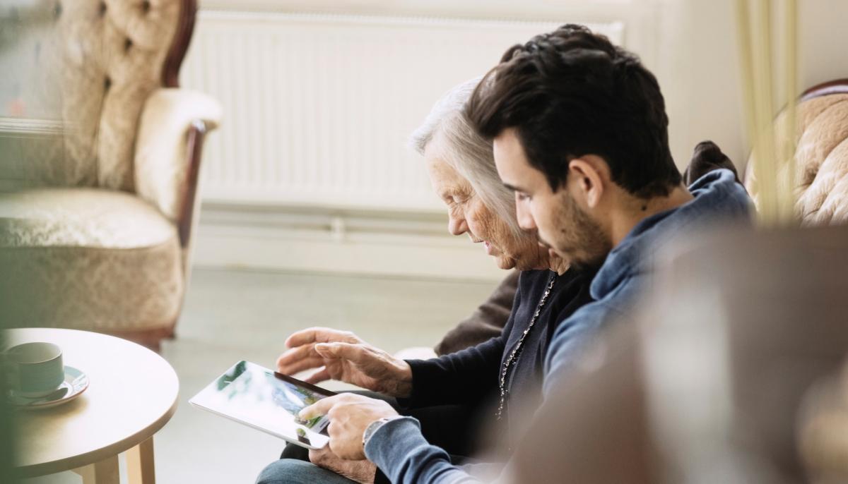 Son helping his mother use a tablet
