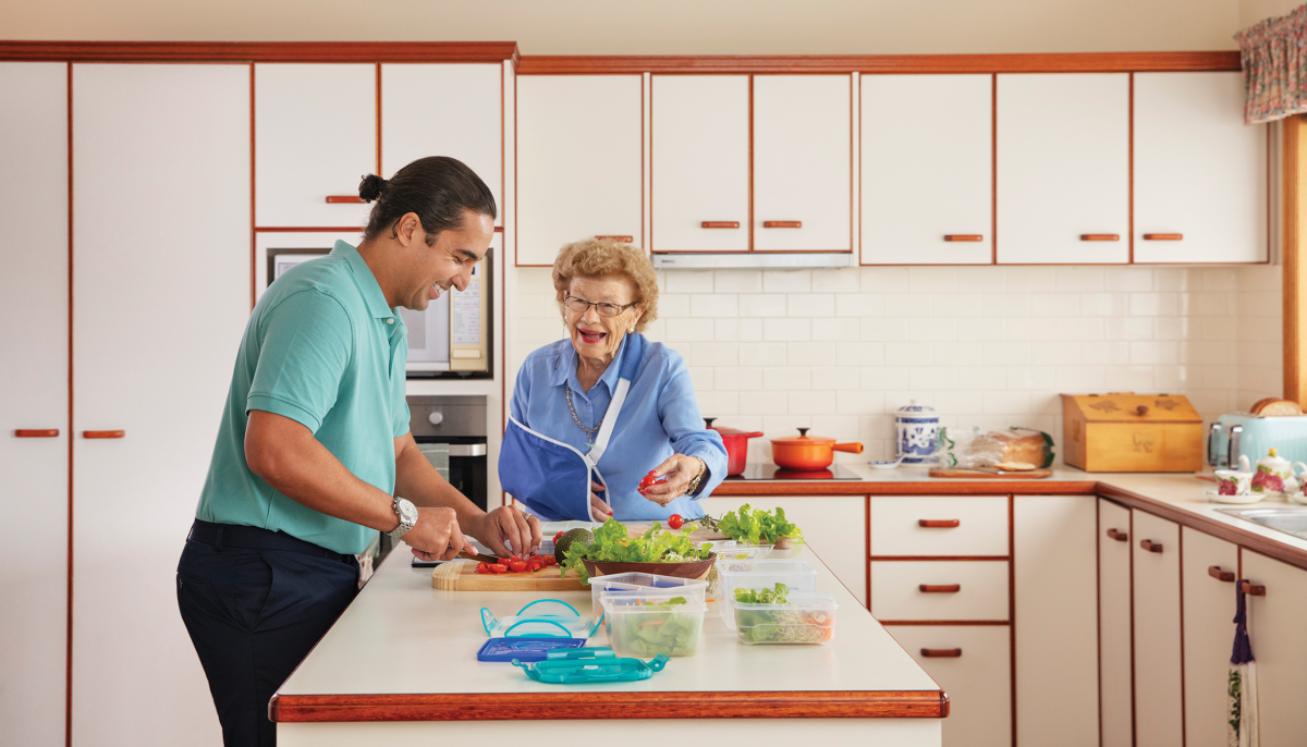 Aged care worker cooking for older woman