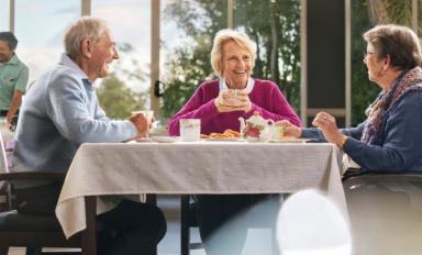 A picture of three older persons having a conversation at a residential aged care home.