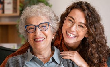 Image description: an older woman and younger woman smiling and looking directly at the viewer.